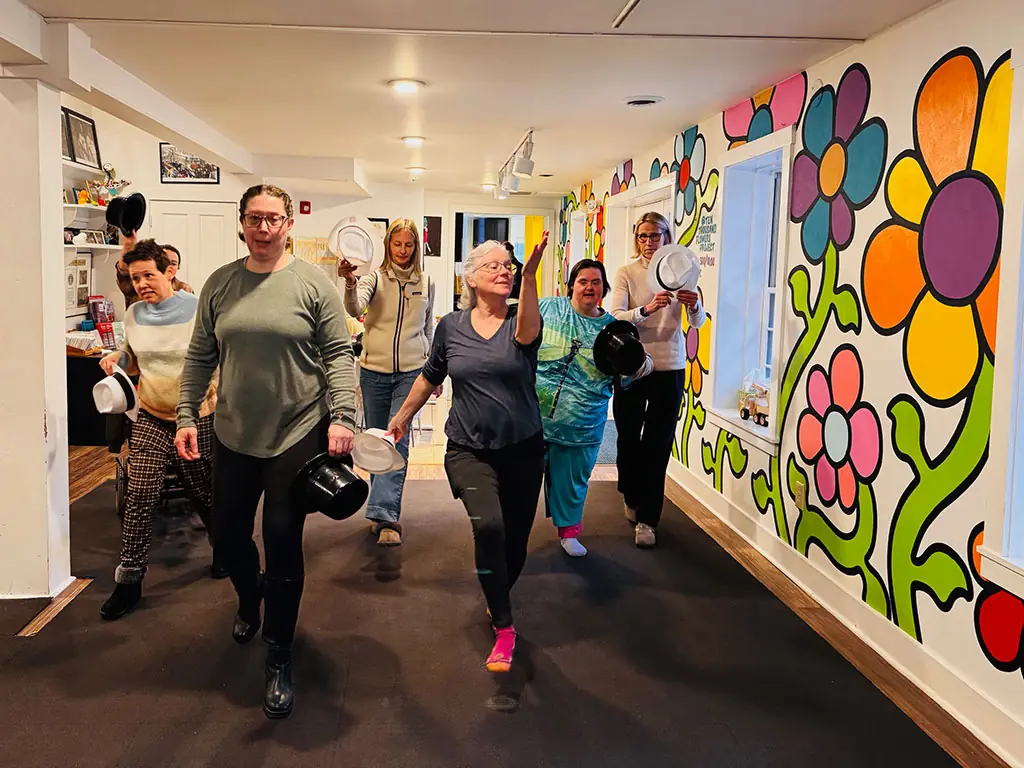Participants and staff walking down a hallway painted with a colorful flower mural