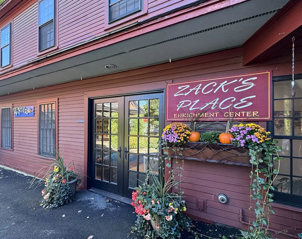 The Zack's Place Enrichment Center entrance with its sign and fall flower boxes