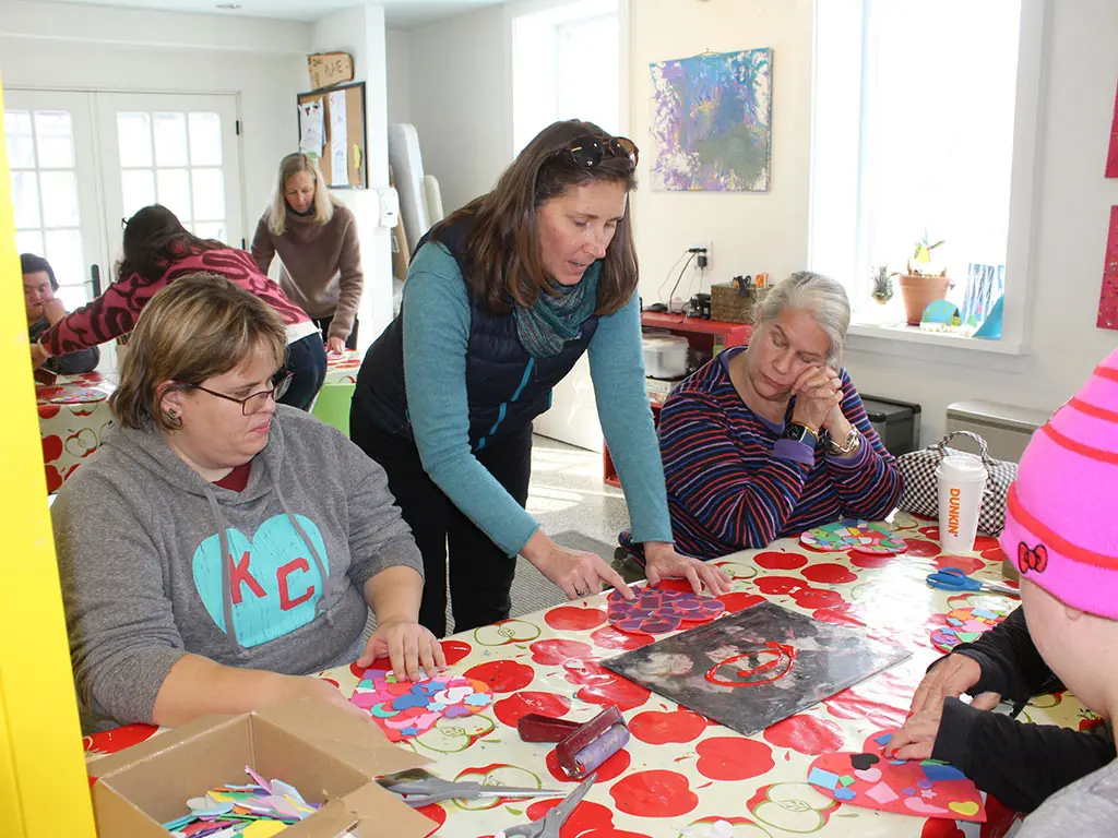 An art instructor helping participants with a collage project at a table