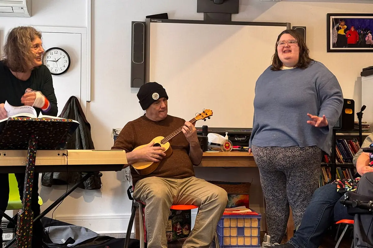 A participant singing while a musician plays the ukulele
