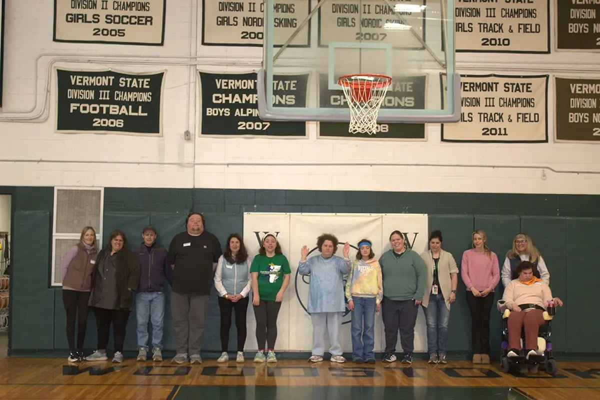 Participants lined up in a school gym under state championship banners