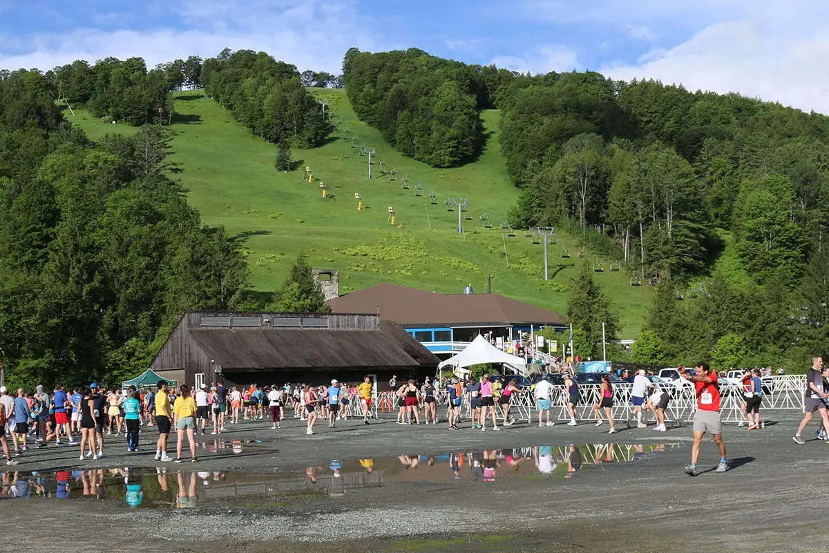 Runners at the Covered Bridges Half Marathon finish area below a green ski slope