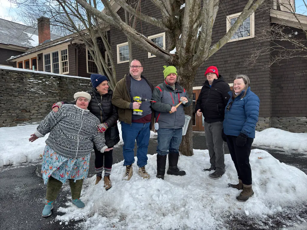 Participants and volunteers standing in the snow outside a stone building