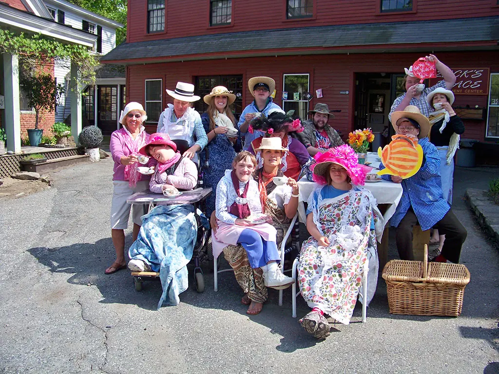 Participants in fancy hats and dresses at an outdoor tea party