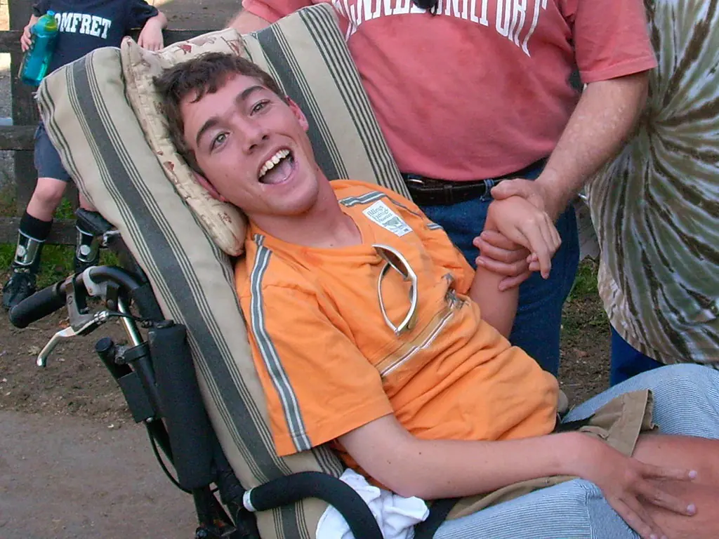 A smiling young man in an orange shirt relaxing outdoors