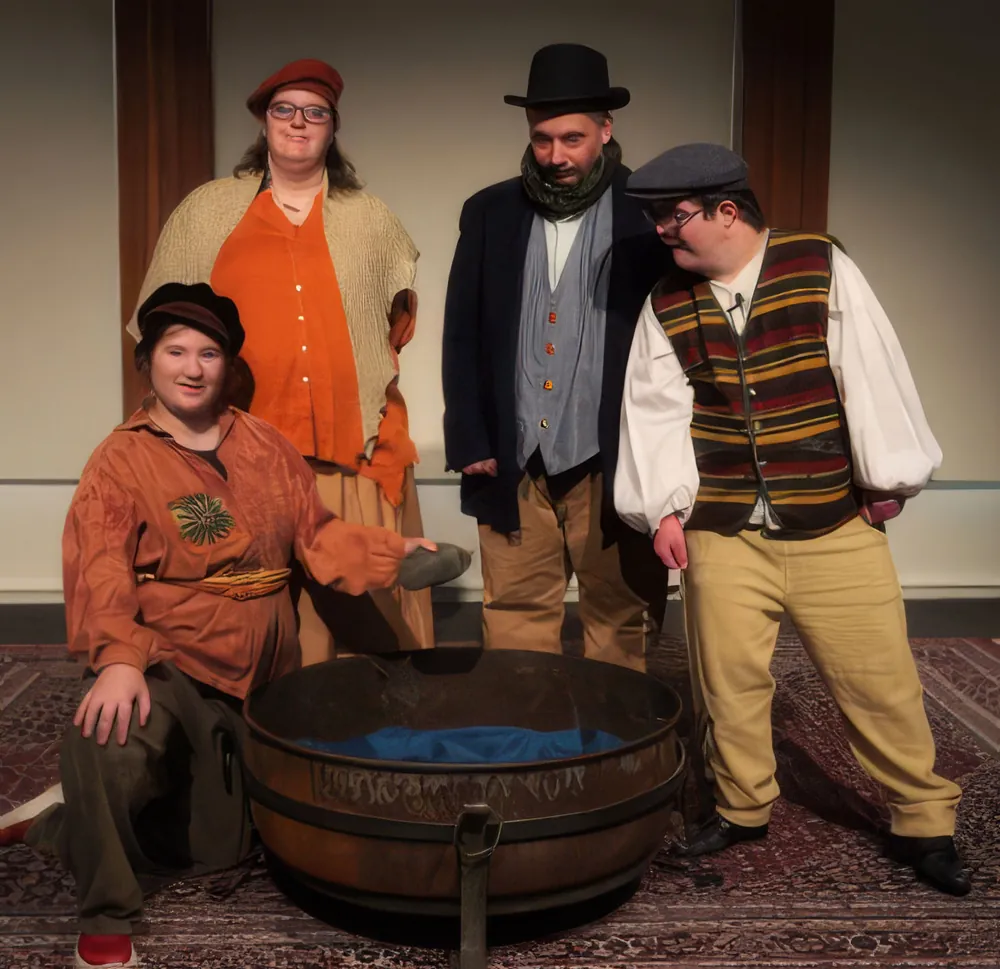Five performers in costume posing around a large wooden tub on stage