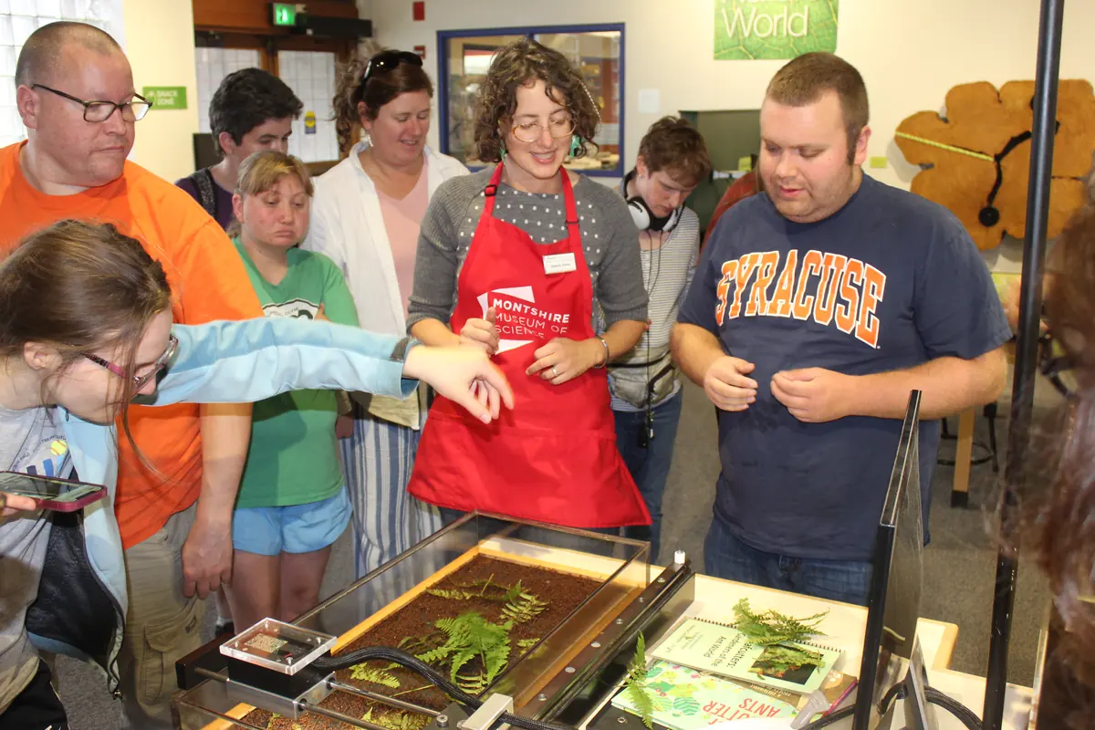 Participants gathered around a hands-on exhibit with a museum educator during a field trip