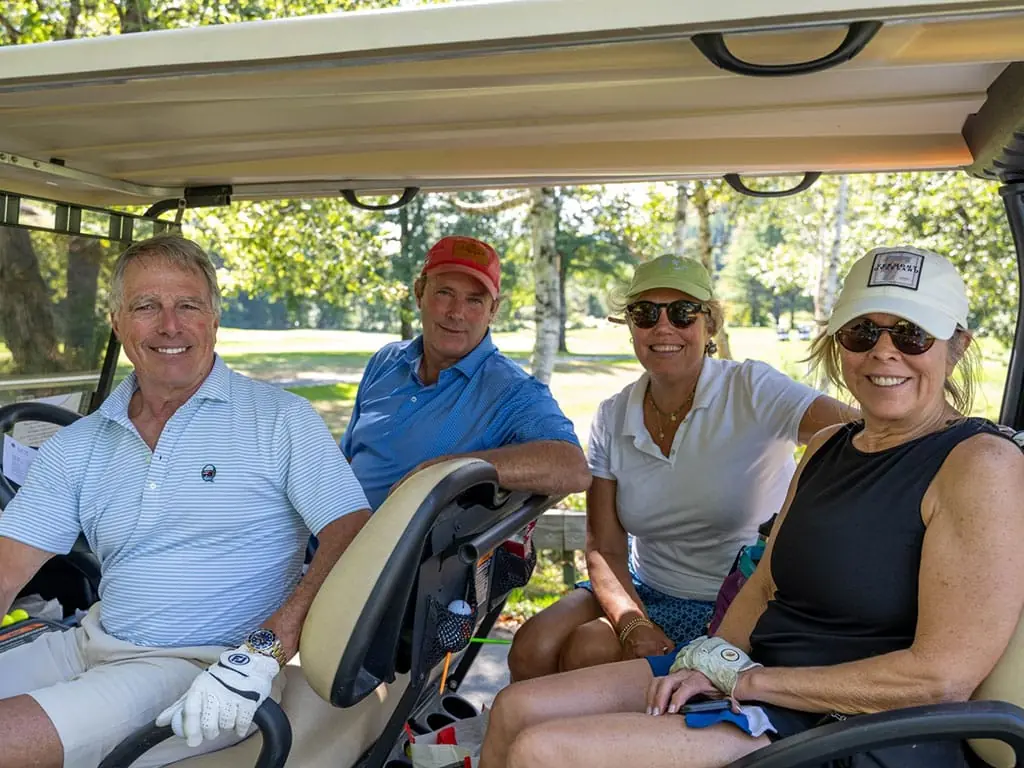 Four golfers smiling from their golf carts